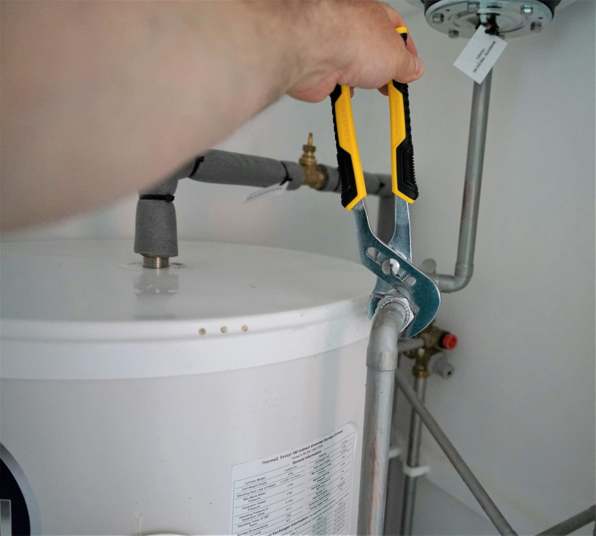 Loodgieter sluit een boiler aan met een waterpomptang
