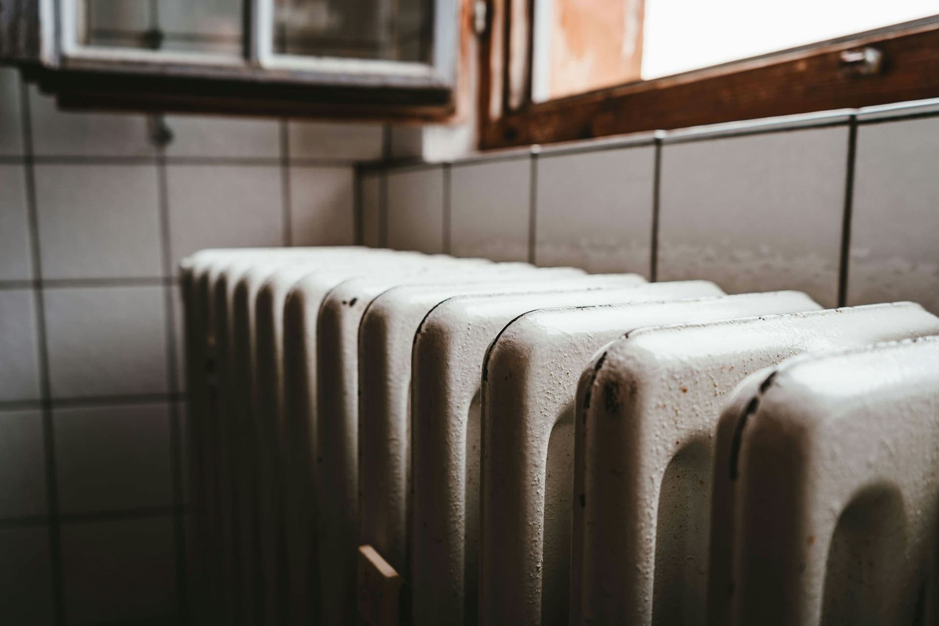 Witte radiator onder een raam in een woning